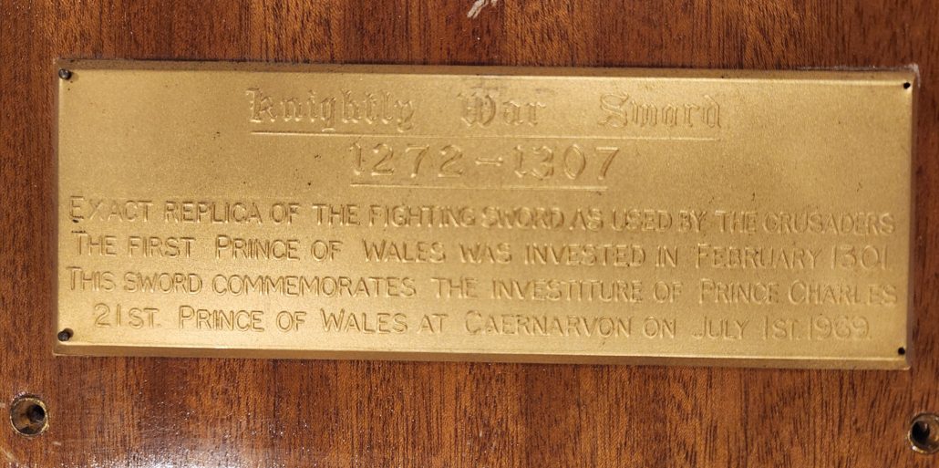 Close-up of the brass plaque attached to the wooden sword holder